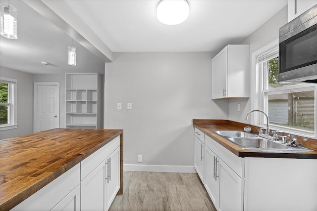 5015 N 25th St, Milwaukee, WI 53209 - kitchen featuring butcher block counters, stainless steel microwave, a sink, baseboards, and white cabinets