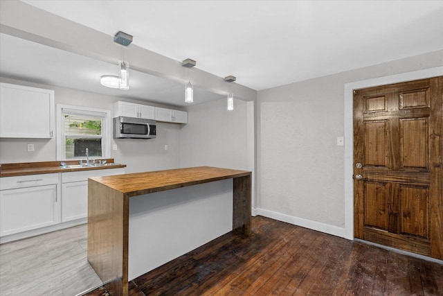 5015 N 25th St, Milwaukee, WI 53209 - kitchen with butcher block countertops, stainless steel microwave, wood finished floors, a sink, and white cabinetry