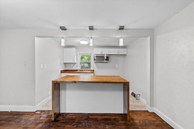 5015 N 25th St, Milwaukee, WI 53209 - kitchen featuring butcher block counters, stainless steel microwave, a sink, white cabinetry, and baseboards