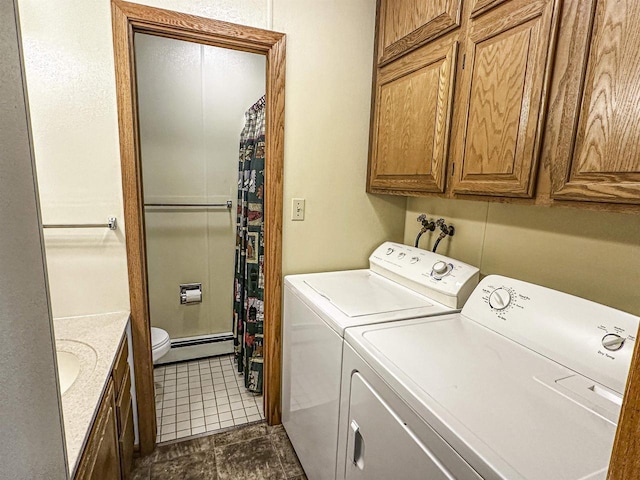 1200 4th Ave N, Park Falls, WI 54552 - laundry area with washing machine and dryer, a baseboard heating unit, dark tile patterned flooring, and cabinet space