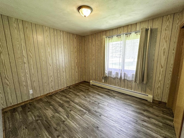 1200 4th Ave N, Park Falls, WI 54552 - unfurnished room with a baseboard heating unit, dark wood-style floors, wooden walls, and baseboards