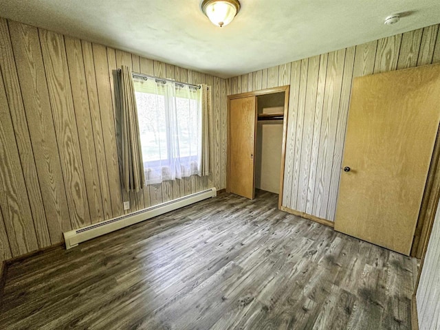 1200 4th Ave N, Park Falls, WI 54552 - unfurnished bedroom featuring a baseboard radiator, wood finished floors, wood walls, and a closet