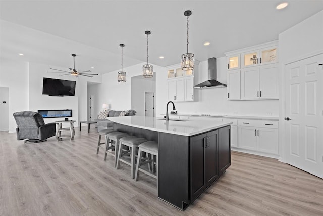1150 S Bay Shore Rd, Brussels, WI 54204 - kitchen featuring wall chimney range hood, a sink, a ceiling fan, light wood finished floors, and white cabinetry