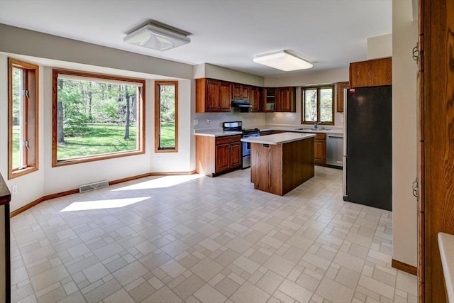 6460 Shady Bend Rd, Verona, WI 53593 - kitchen with stainless steel appliances, baseboards, light countertops, a sink, and under cabinet range hood
