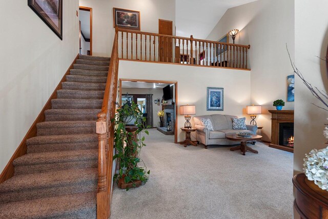 N3154 River Bend Dr, Peshtigo, WI 54157 - carpeted living room with a lit fireplace, stairway, and a high ceiling