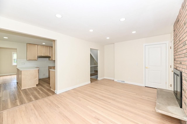 9530 W Debbie Ln, Milwaukee, WI 53224 - unfurnished living room featuring a brick fireplace, light wood finished floors, recessed lighting, baseboards, and brick wall