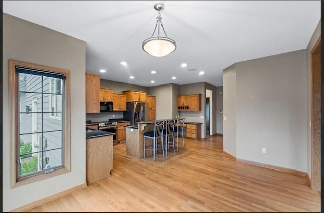 2605 River Ridge Drive, Waukesha, WI 53189 - kitchen featuring stainless steel appliances, baseboards, light wood finished floors, a kitchen breakfast bar, and brown cabinets