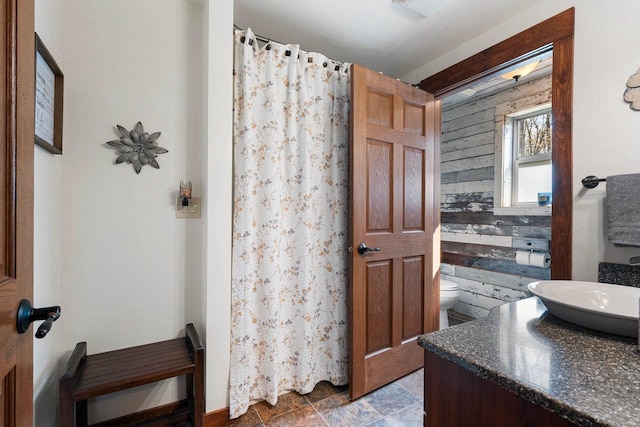 15393 Jacklin Heights Cir, Crivitz, WI 54114 - bathroom featuring toilet, vanity, a shower with curtain, wood walls, and stone finish floors