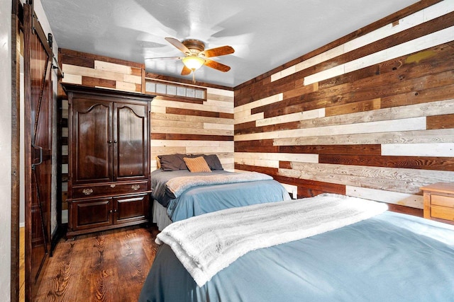 15393 Jacklin Heights Cir, Crivitz, WI 54114 - bedroom featuring wooden walls, dark wood-style flooring, a barn door, and ceiling fan