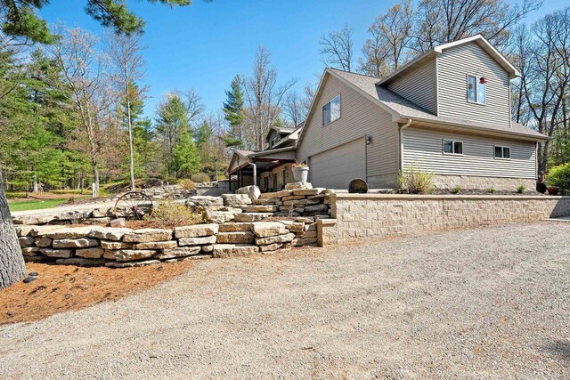 15393 Jacklin Heights Cir, Crivitz, WI 54114 - view of side of home featuring dirt driveway, an attached garage, and a shingled roof
