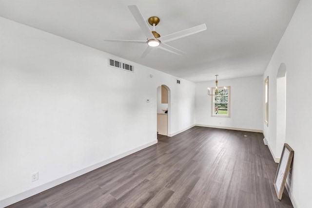 427 Robbins St, Seymour, WI 54165 - empty room featuring arched walkways, ceiling fan, dark wood-style flooring, a chandelier, and baseboards