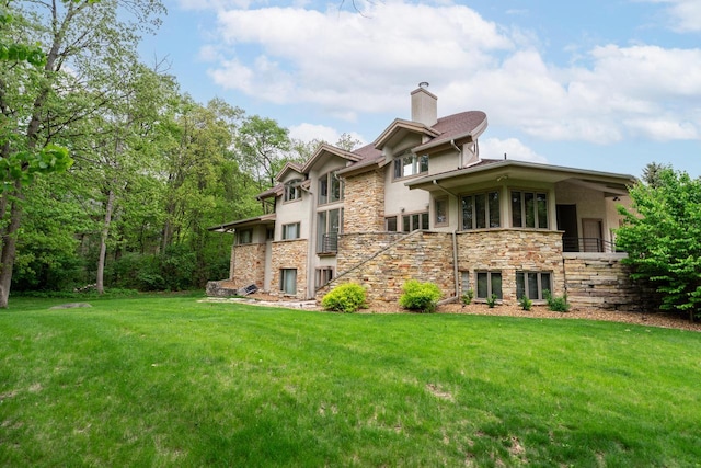 58 Oakridge Ct, Fond Du Lac, WI 54937 - back of house featuring a chimney, stone siding, a yard, and stucco siding