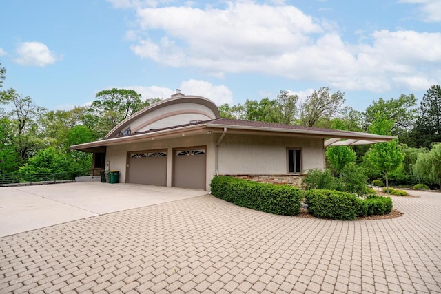 58 Oakridge Ct, Fond Du Lac, WI 54937 - view of side of property with concrete driveway, an attached garage, stone siding, stucco siding, and view of scattered trees