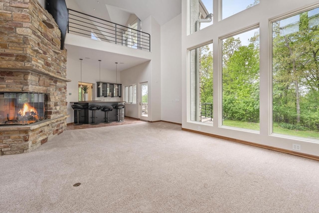 58 Oakridge Ct, Fond Du Lac, WI 54937 - unfurnished living room featuring carpet floors, baseboards, a towering ceiling, and a stone fireplace