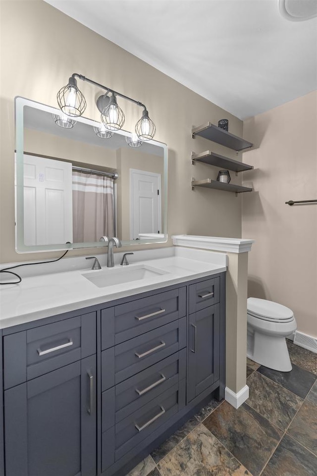 522 Valley Rd, Madison, WI 53714 - bathroom featuring vanity, toilet, baseboards, and stone finish flooring