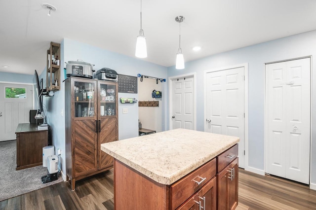 900 Edgewater Dr, Merrill, WI 54452 - kitchen with dark wood finished floors, hanging light fixtures, a center island, light countertops, and brown cabinetry