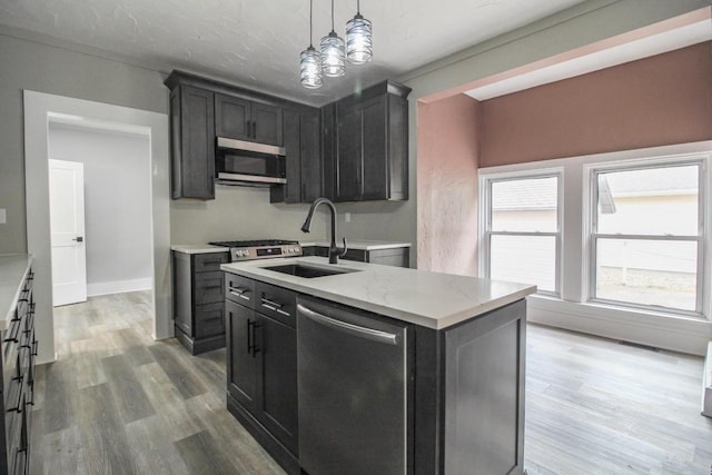 139 S Church St, Whitewater, WI 53190 - kitchen featuring appliances with stainless steel finishes, a sink, light wood finished floors, a kitchen island with sink, and light stone counters