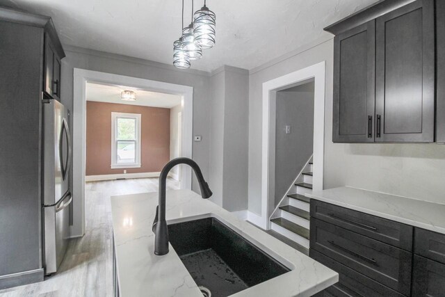 139 S Church St, Whitewater, WI 53190 - kitchen featuring freestanding refrigerator, a sink, light stone counters, decorative light fixtures, and dark cabinetry