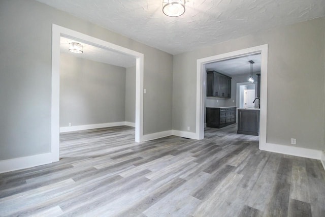 139 S Church St, Whitewater, WI 53190 - unfurnished living room featuring baseboards, light wood-type flooring, and a textured ceiling
