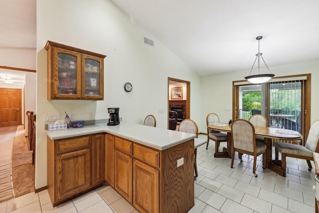 615 Jefferson St, Waterloo, WI 53594 - kitchen with vaulted ceiling, light countertops, glass insert cabinets, brown cabinetry, and light tile patterned floors