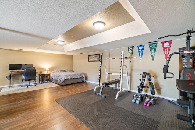3829 Nicholas Dr, Menomonie, WI 54751 - bedroom featuring a tray ceiling, a textured ceiling, baseboards, and wood finished floors