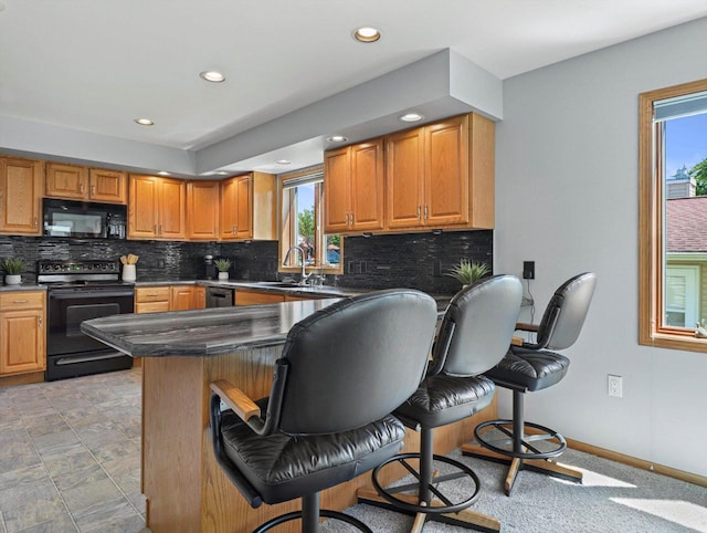 1306 Neponset Trl, Monona, WI 53716 - kitchen with black appliances, a breakfast bar, healthy amount of natural light, a sink, and recessed lighting