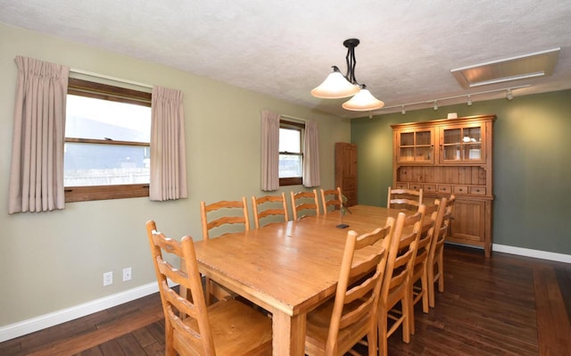 2462 Wallace Lake Rd, West Bend, WI 53090 - dining area featuring baseboards, rail lighting, dark wood-style floors, and a textured ceiling
