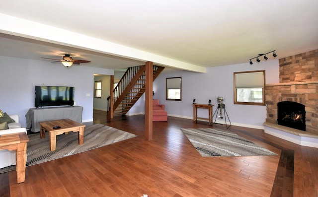 2462 Wallace Lake Rd, West Bend, WI 53090 - unfurnished living room featuring stairs, track lighting, wood finished floors, a stone fireplace, and baseboards