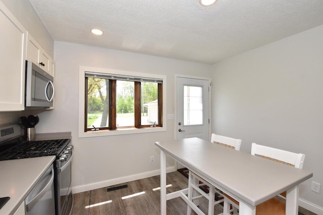 2462 Wallace Lake Rd, West Bend, WI 53090 - kitchen with appliances with stainless steel finishes, dark wood-style floors, white cabinets, a textured ceiling, and baseboards