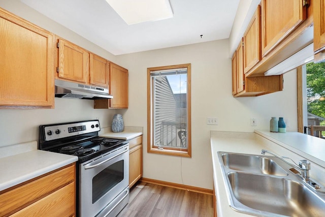 6911 Raymond Rd, Madison, WI 53711 - kitchen with under cabinet range hood, electric range, a sink, light wood-style flooring, and light countertops