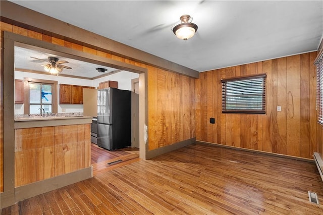 1020 E 10th St, Menomonie, WI 54751 - kitchen with freestanding refrigerator, brown cabinetry, wood-type flooring, light countertops, and wooden walls
