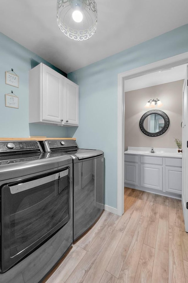 5806 E Open Mdw, Mcfarland, WI 53558 - laundry room featuring washing machine and clothes dryer, light wood-style flooring, cabinet space, and baseboards