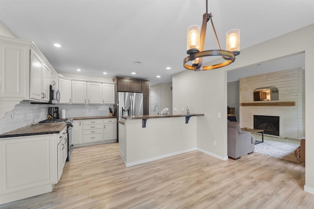 5806 E Open Mdw, Mcfarland, WI 53558 - kitchen with dark countertops, stainless steel appliances, a kitchen bar, a chandelier, and light wood-style flooring