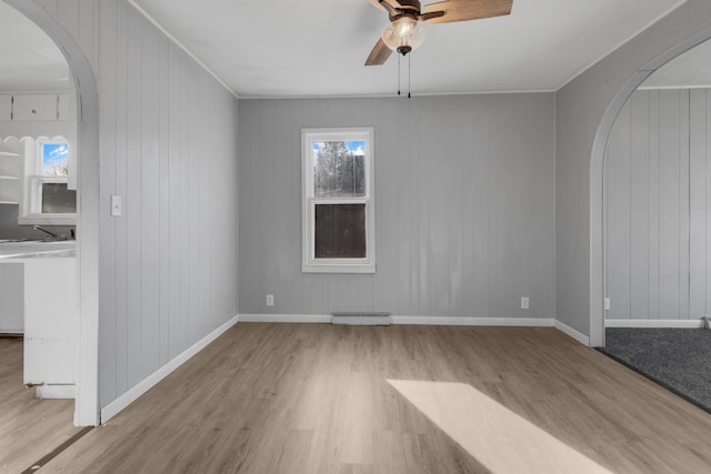 924 N Stevens St, Rhinelander, WI 54501 - spare room with arched walkways, ceiling fan, wood finished floors, baseboards, and wooden walls