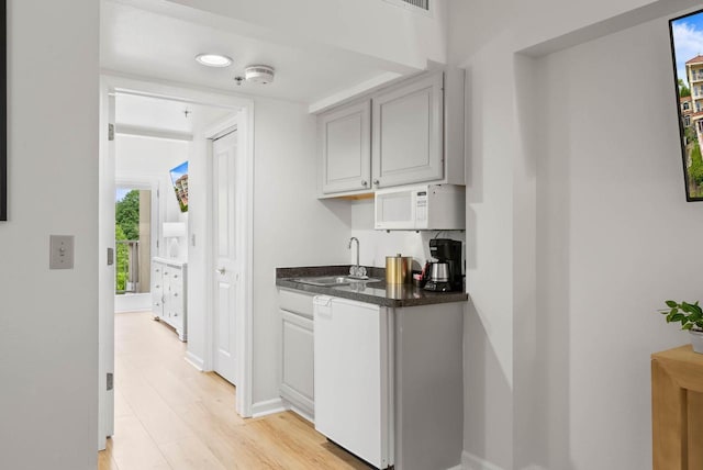 335 Wrigley Dr Unit 411, Lake Geneva, WI 53147 - bar area featuring white microwave, a sink, light wood-style flooring, baseboards, and dishwasher