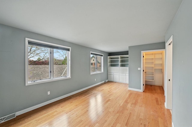 1420 N Astor St, Milwaukee, WI 53202 - unfurnished bedroom with light wood-style floors, baseboards, a closet, and a walk in closet