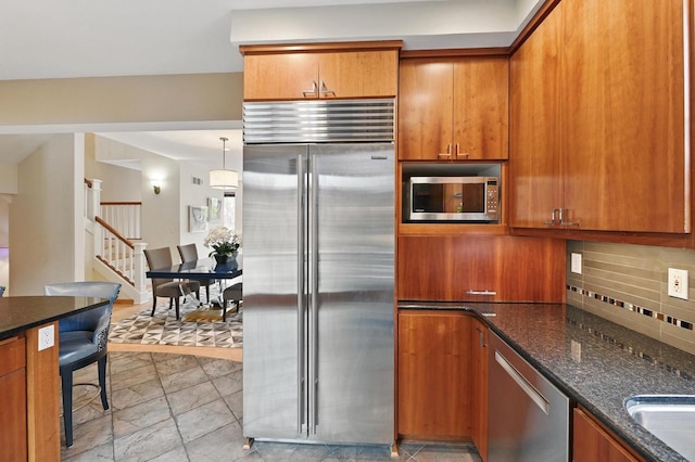 1420 N Astor St, Milwaukee, WI 53202 - kitchen featuring built in appliances, brown cabinetry, tasteful backsplash, and dark stone counters