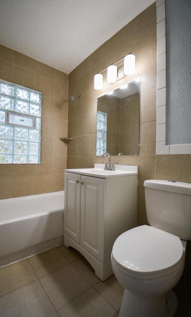 4646 N 51st Blvd, Milwaukee, WI 53218 - bathroom featuring tile patterned floors, toilet, vanity, tile walls, and tub / shower combination