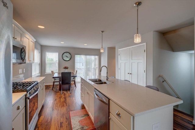 9327 Silicon Prairie Pkwy, Verona, WI 53593 - kitchen featuring appliances with stainless steel finishes, a sink, dark wood finished floors, a center island with sink, and white cabinets