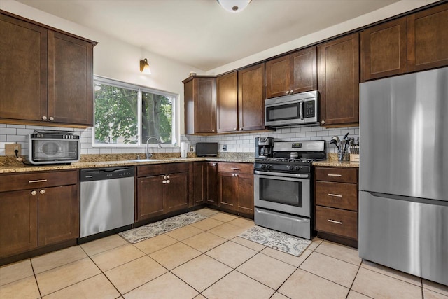 2207 N 51st St, Milwaukee, WI 53208 - kitchen featuring stainless steel appliances, a sink, tasteful backsplash, dark brown cabinetry, and light tile patterned floors