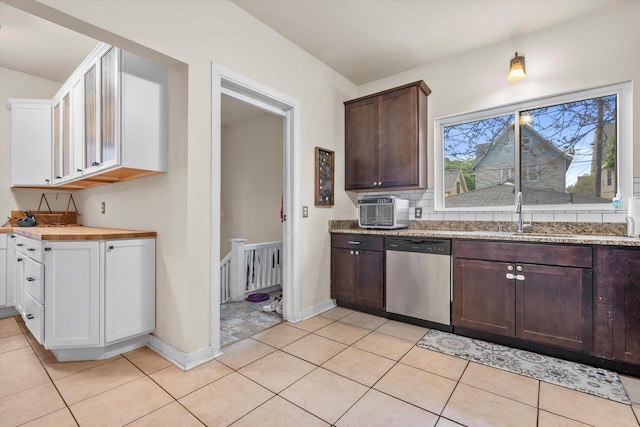 2207 N 51st St, Milwaukee, WI 53208 - kitchen featuring stainless steel dishwasher, a sink, dark brown cabinets, light tile patterned floors, and white cabinetry