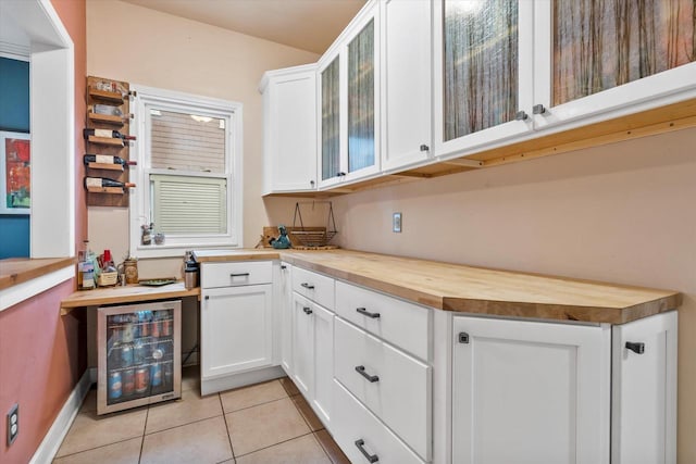 2207 N 51st St, Milwaukee, WI 53208 - kitchen with butcher block countertops, beverage cooler, light tile patterned flooring, glass insert cabinets, and white cabinets