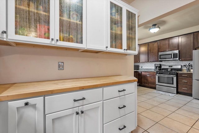 2207 N 51st St, Milwaukee, WI 53208 - kitchen featuring stainless steel appliances, butcher block counters, light tile patterned floors, decorative backsplash, and dark brown cabinetry