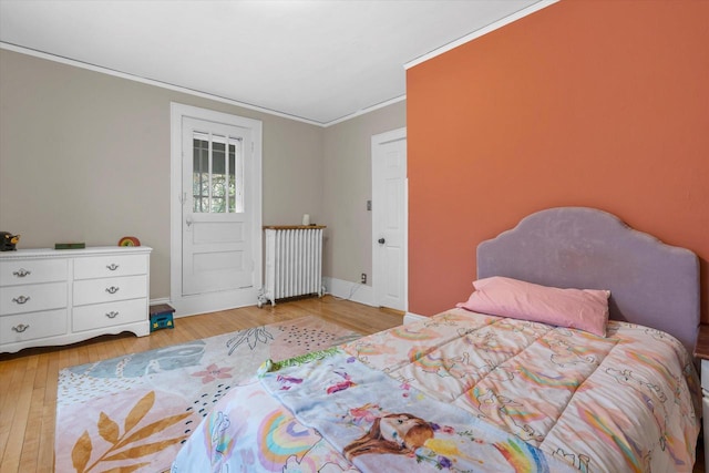 2207 N 51st St, Milwaukee, WI 53208 - bedroom with radiator heating unit, ornamental molding, light wood-style flooring, and baseboards
