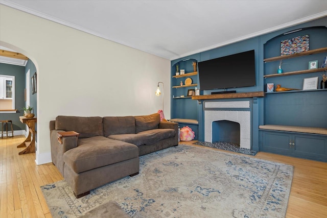2207 N 51st St, Milwaukee, WI 53208 - living room with crown molding, a tiled fireplace, hardwood / wood-style floors, arched walkways, and built in features
