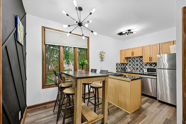 2504 S Delaware Ave Unit 102, Milwaukee, WI 53207 - kitchen with stainless steel appliances, a chandelier, dark countertops, backsplash, and dark wood-style flooring