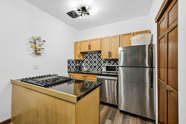 2504 S Delaware Ave Unit 102, Milwaukee, WI 53207 - kitchen featuring appliances with stainless steel finishes, dark countertops, tasteful backsplash, dark wood-type flooring, and a peninsula