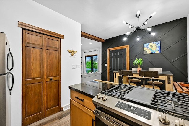 2504 S Delaware Ave Unit 102, Milwaukee, WI 53207 - kitchen with appliances with stainless steel finishes, wood finished floors, a chandelier, dark countertops, and brown cabinets