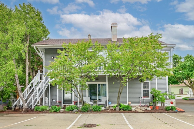 2504 S Delaware Ave Unit 102, Milwaukee, WI 53207 - rear view of property featuring a porch, uncovered parking, a chimney, and stairway