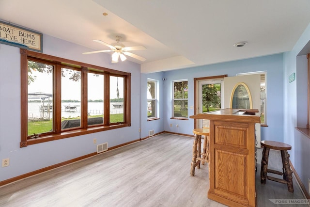 2894 Waubesa Ave, Madison, WI 53711 - dining room featuring light wood-type flooring, ceiling fan, baseboards, a water view, and a bar